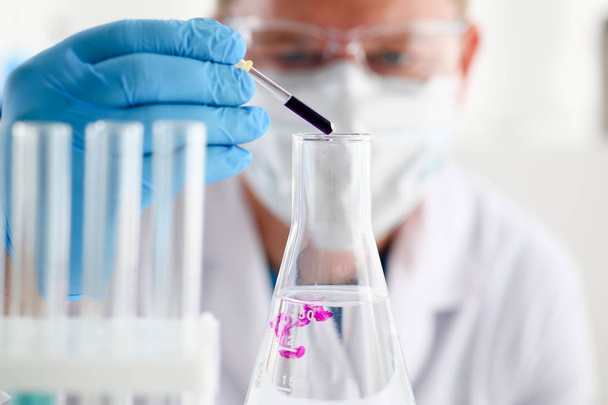 Ένα αρσενικό χημικός κατέχει δοκιμαστικό σωλήνα από γυαλί - Φωτογραφία, εικόνα