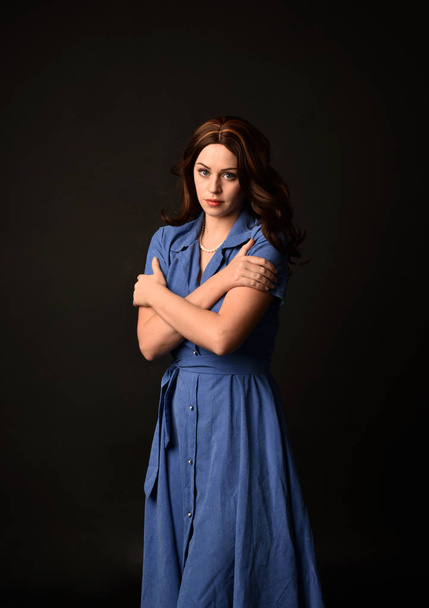 3/4 portrait of brunette lady wearing blue dress. posed on black studio background. - 写真・画像