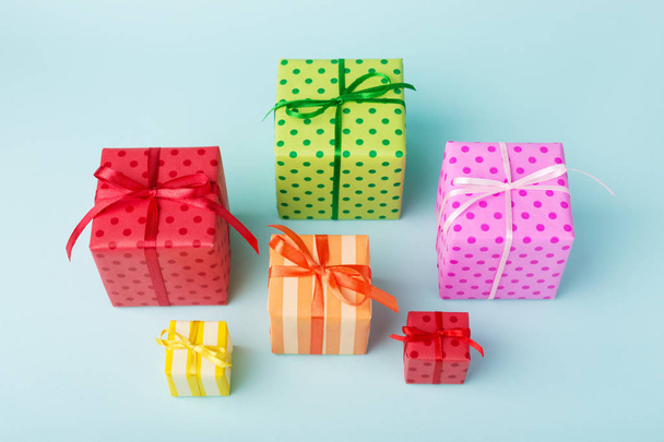 Різні святкові барвисті подарункові коробки, загорнуті в барвистий папір і банти на синьому фоні. День народження, різдвяний настрій та концепція продажу
. - Фото, зображення