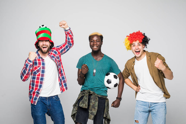 Yes. Winners. Three cheerful young men are standing and gesturing for the victory on white background in casual outfit and jeans. - Photo, Image