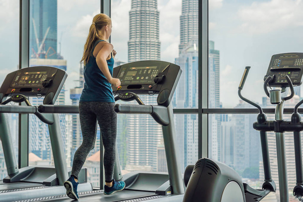 sport, fitness, lifestyle, technology and people concept - woman exercising on treadmill in gym against the background of a big city. - Foto, Imagem