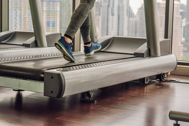 sport, fitness, lifestyle, technology and people concept - woman exercising on treadmill in gym against the background of a big city. - Foto, Bild