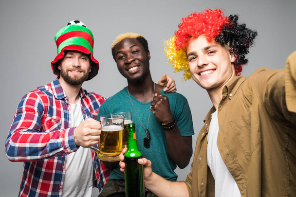 Holidays leisure funtime football soccer fan concept. Friendly three mixed race excited cheerful guys making selfie isolated on white background - Photo, Image