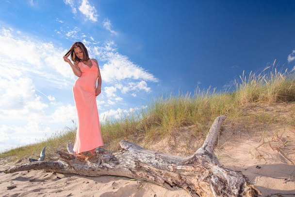 Красивая женщина в розовом платье на песчаном пляже Балтийского моря
. - Фото, изображение