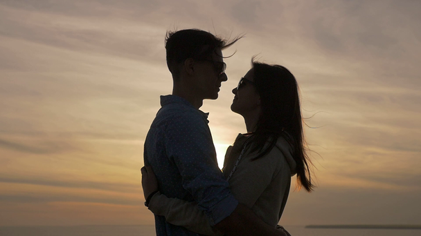 Young people hug each other erotically on the Black Sea coast at sunset                                 Profile of a young woman embracing her enchanted sweetheart on the Black Sea shore at wonderful sunset with a shining sun path in summer - Footage, Video