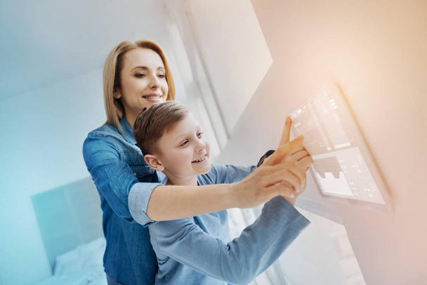 Smiling boy pressing his finger to the screen and his mother helping him - Photo, Image