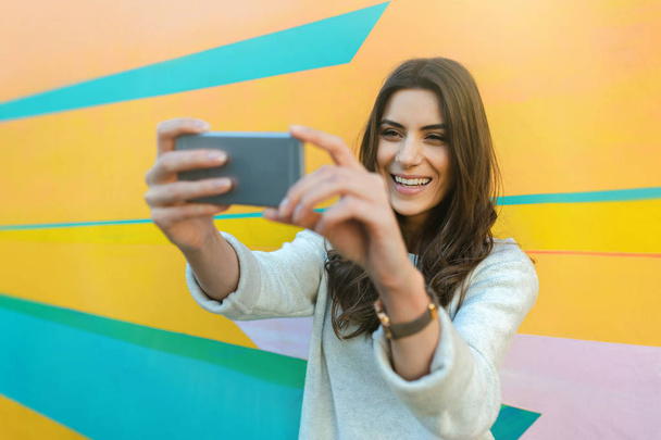 Hipster mulher tirar fotos selfie em fundo abstrato colorido
 - Foto, Imagem