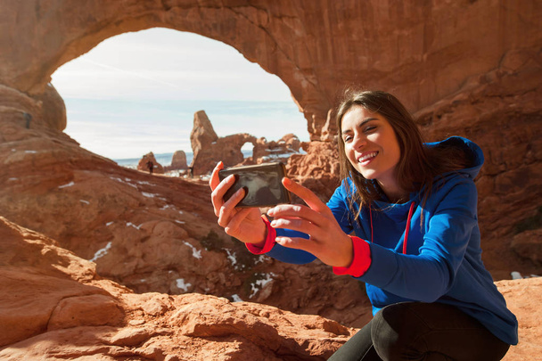 Feminino viajante taikng auto-retratos com formação de rocha no Parque Nacional dos Arcos, Utah, EUA
 - Foto, Imagem