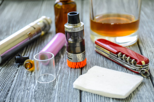 Still life with e-cig and jiuce on the wooden background - Photo, Image