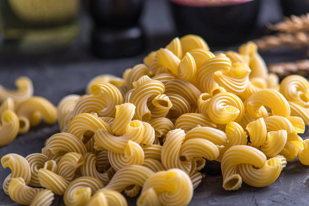Kypsentämättömät italialaiset pastat spiraalien muodossa tummalla taustalla. Elintarvikkeiden koostumuksen käsite
. - Valokuva, kuva