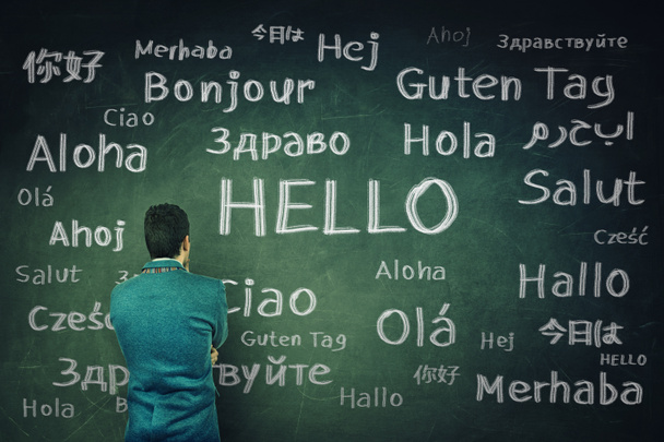 Rear view of a puzzled businessman in front of a huge chalkboard written with the word hallo in different languages. Opportunity for learning new languages for students. - Fotoğraf, Görsel