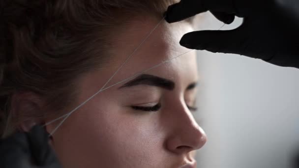 Removing small hairs from face with thread in beauty salon, depilation with thread, threading in beauty salon, facial treatment, cosmetic manipulation - Footage, Video