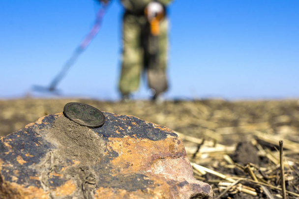 de oude munt in het veld, op de onscherpe achtergrond van de Jager van de schat met een metaaldetector verloren - Foto, afbeelding