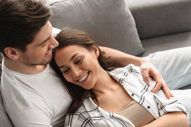 Photo of beautiful couple man and woman smiling and resting together in living room at home - Foto, Imagem