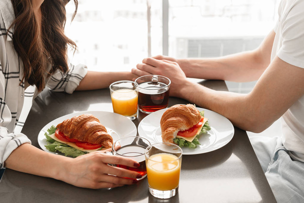 Image cropped of caucasian man and woman having breakfast or dinner at home in morning - Foto, afbeelding