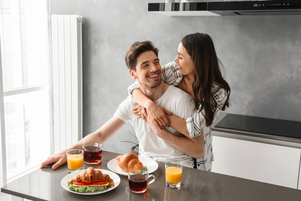 Portait of gorgeous couple smiling and enjoying time together while hugging during breakfast in house - Foto, immagini