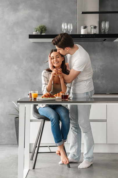 Портрет влюбленной пары в полный рост, улыбающейся и смотрящей на вас, сидя за столом с едой
 - Фото, изображение