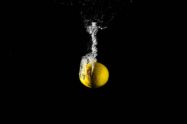 Lemon drop in water black background - Фото, зображення