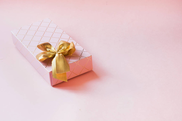 Female gift box with golden ribbon on punchy pastel pink. Birthday. Copy space. Top view. - Φωτογραφία, εικόνα