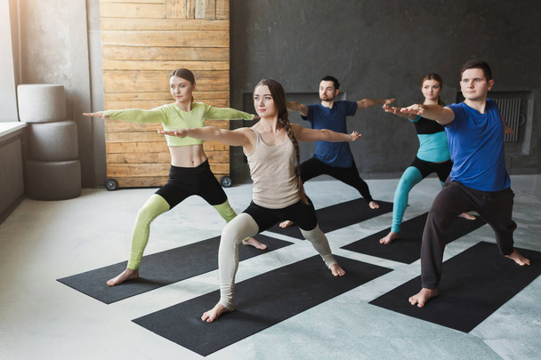 Mladé ženy a muži v třídě jógy, dělá protahovací cvičení - Fotografie, Obrázek