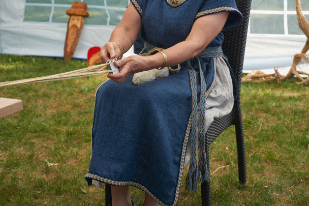 Mulher em roupas tradicionais fazendo artesanato usando cordas finas naturais em uma visão cortada de perto
 - Foto, Imagem