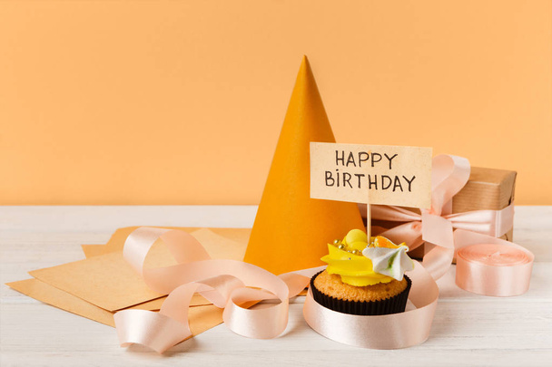 Delicioso cupcake y regalo sobre fondo amarillo
 - Foto, imagen