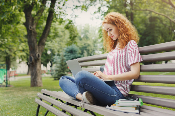 Happy student is using laptop in the park - Photo, Image