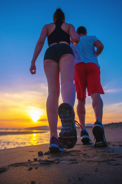 Homem e mulher correndo na praia tropical ao pôr do sol
 - Foto, Imagem