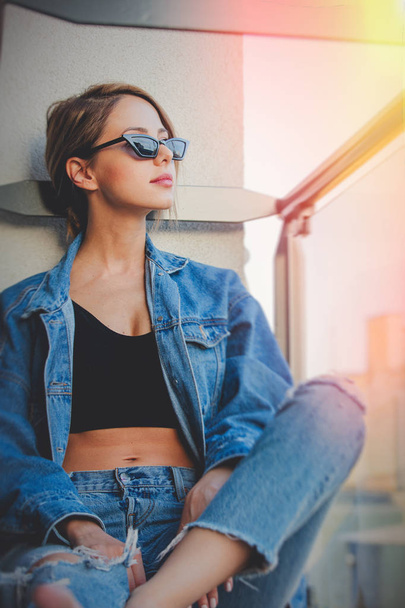chica en jeans ropa y gafas de sol en balcón
 - Foto, imagen