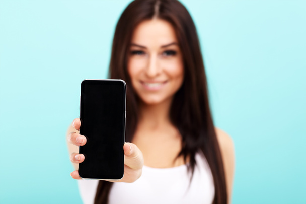 Femme utilisant un smartphone sur fond de mur bleu
 - Photo, image