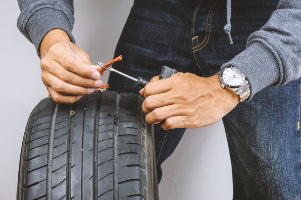 El hombre que repara el neumático plano del coche con el equipo de reparación, equipo de reparación del enchufe de neumático para los neumáticos tubeless
. - Foto, Imagen