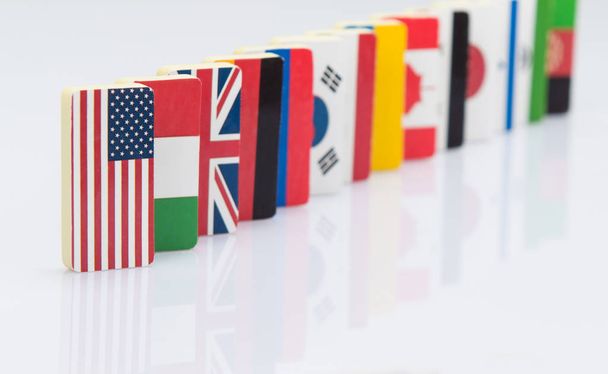 der Dominoeffekt mit Fliesen von Flaggen verschiedener Länder der Welt. Konzeptfoto, politische Spielchen. Studioaufnahmen - Foto, Bild