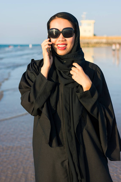 Žena v abaya má telefonní hovor na pláži - Fotografie, Obrázek