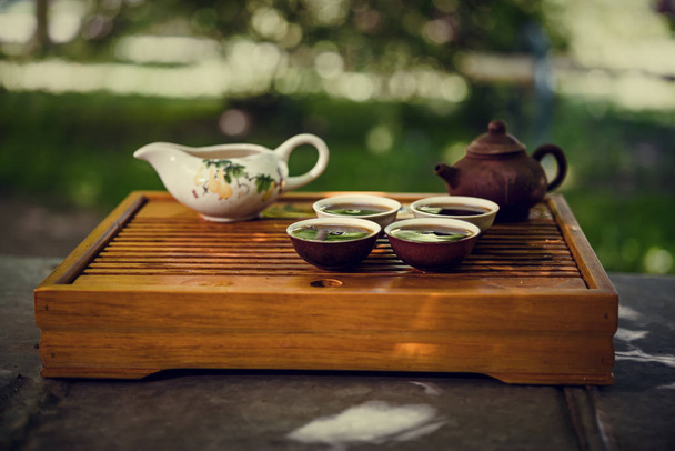 Teapot, bowl and four cups. Drinking Puer tea in nature. - Photo, image