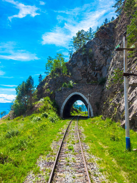 Luminoso sfondo per viaggi e turismo in Siberia con vecchio tunnel ad arco in pietra in montagna la roccia sulla ferrovia Circum-Baikal. Paesaggio estivo con primo piano sfocato
 - Foto, immagini