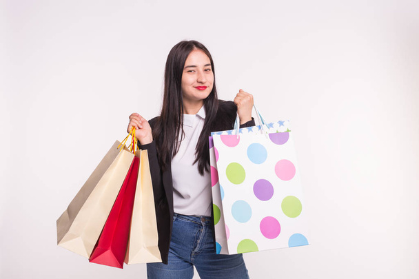 Porträt einer jungen glücklichen brünetten Frau mit Einkaufstaschen auf weißem Hintergrund - Foto, Bild
