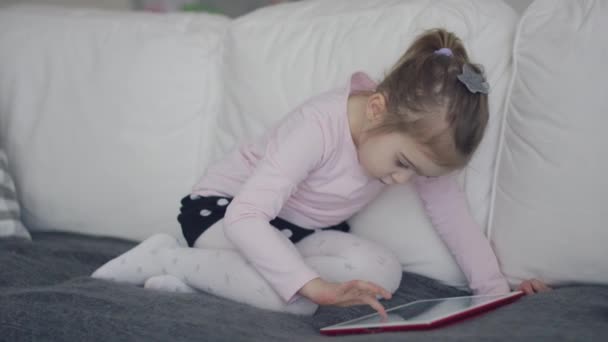 Casual girl using tablet on sofa - Filmati, video