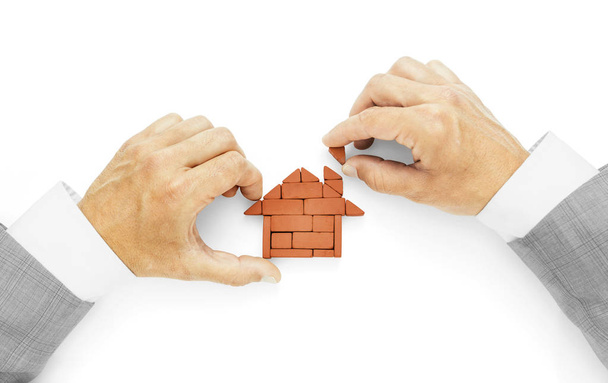 Metaphor of building a house, the last brick, completion of works.Businessman hands using bricks for building house on white background, including clipping path - Fotó, kép
