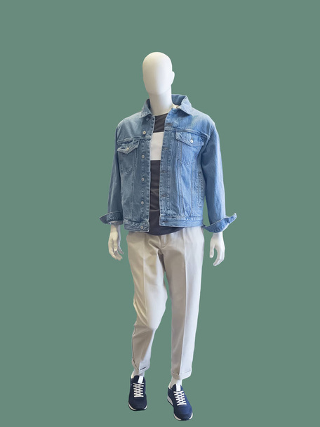Full-length male mannequin dressed in jeans jacket and white trousers, isolated on green background. No brand names or copyright objects. - Photo, Image