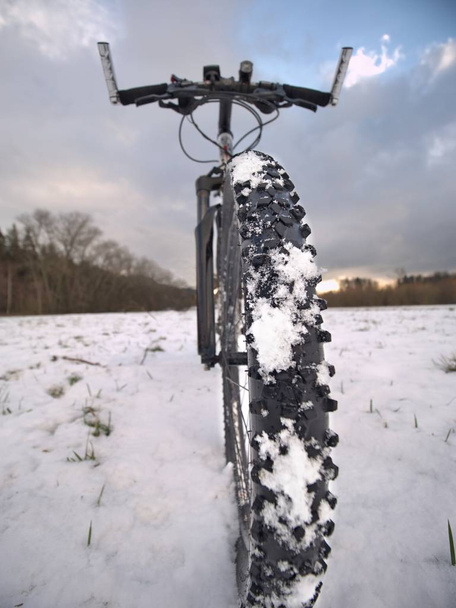 Detalle de la bicicleta delantera en un sendero de invierno, camino cubierto de nieve. Fondos deportivos y naturalezas muertas. Ciclismo en el campo
. - Foto, imagen