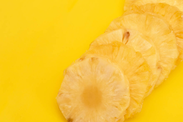 Circles cut peeled pineapple slices on yellow background - Photo, Image