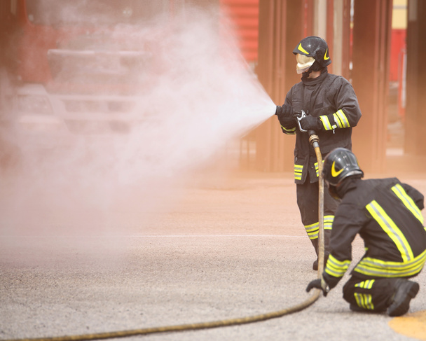 пожарный в маске тушит огонь белой пеной
 - Фото, изображение