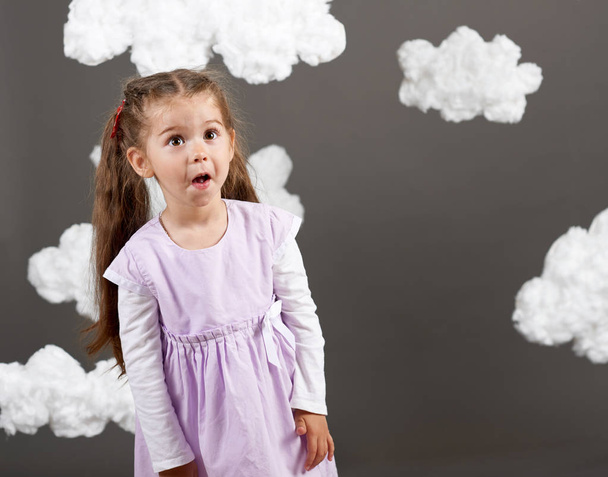 tyttö leikkii pilvet, ammunta studiossa harmaalla pohjalla, onnellinen lapsuuden käsite
 - Valokuva, kuva