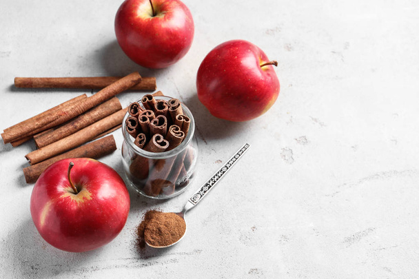 Fresh apples with cinnamon sticks and powder on table - Фото, зображення