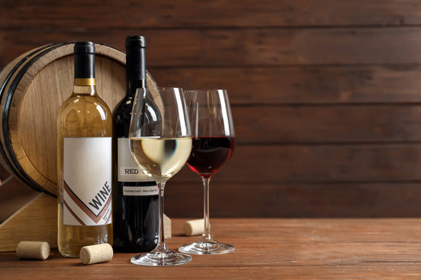 Γυαλιά με γευστικό κρασί, μπουκάλια και βαρέλι στο τραπέζι - Φωτογραφία, εικόνα