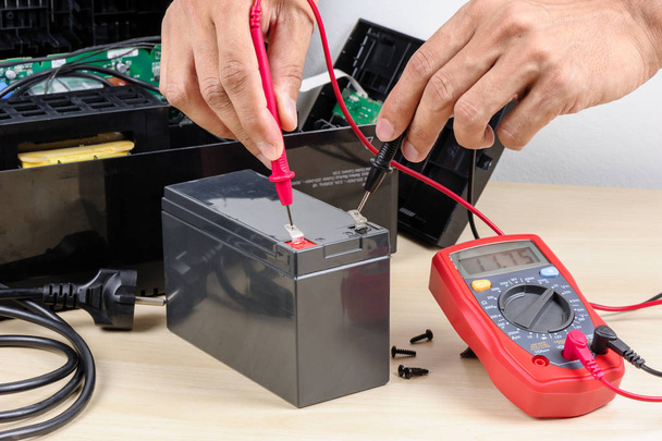 Technicien mesurant la tension de la batterie pour UPS (Uninterruptible Power Supply) avec multimètre
. - Photo, image