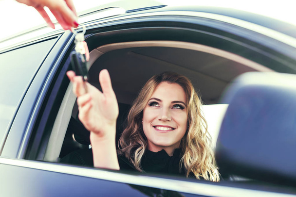 Приваблива жінка в машині отримує ключі від машини. Оренда або купівля автомобіля
. - Фото, зображення