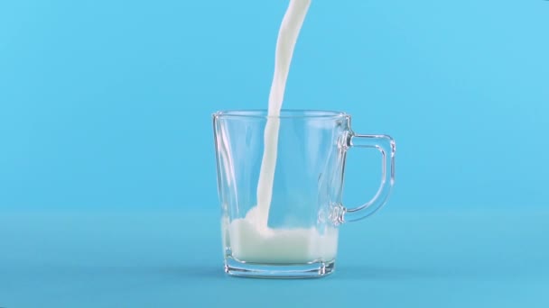 Повільний рух крупним планом знімок молока холодного напою, який бідняк у скляний кухоль з ручкою на синьому фоні в студії
 - Кадри, відео