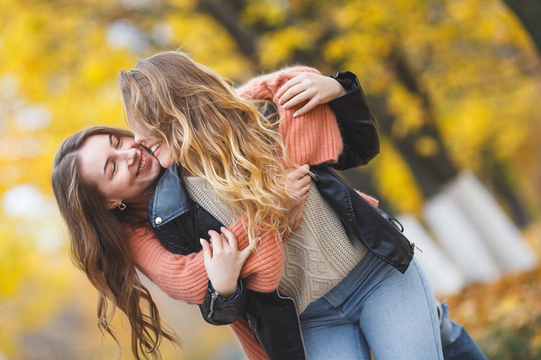 Young pretty girls having fun outdoors in autumn background. Cheerful friends in the fall time - Foto, immagini