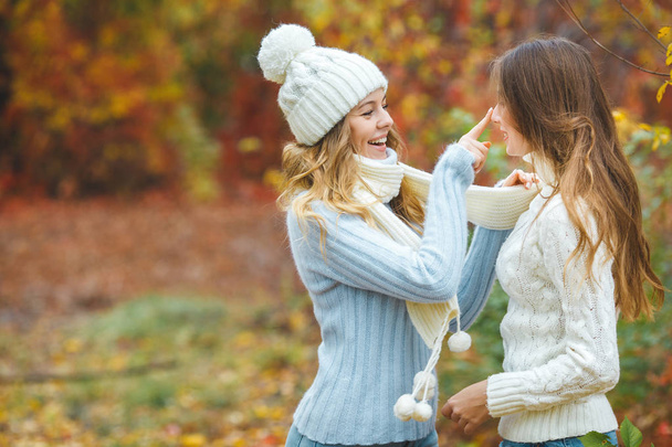 Young pretty girls having fun outdoors in autumn background. Cheerful friends in the fall time - Fotó, kép